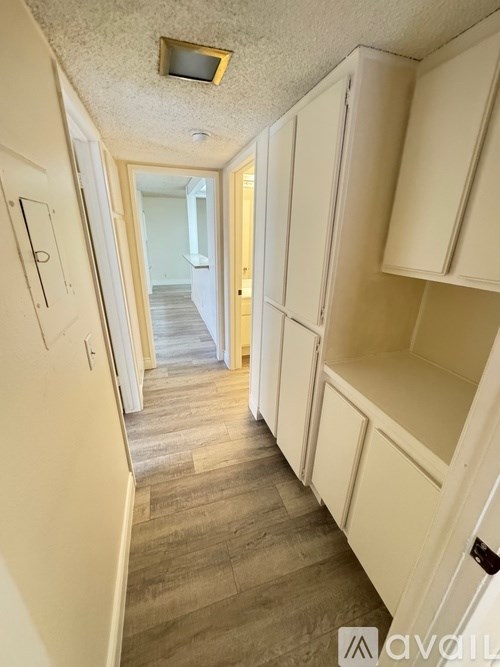 A long hallway with white cabinets on the side and a door at the end.
