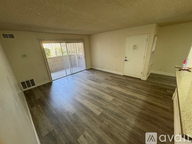 A room with wooden flooring and a sliding glass door.