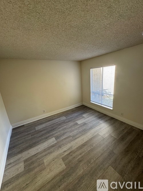 A room with wooden flooring and a window with blinds.