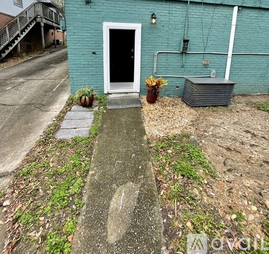 A blue building with a white door and a concrete pathway leading to it.
