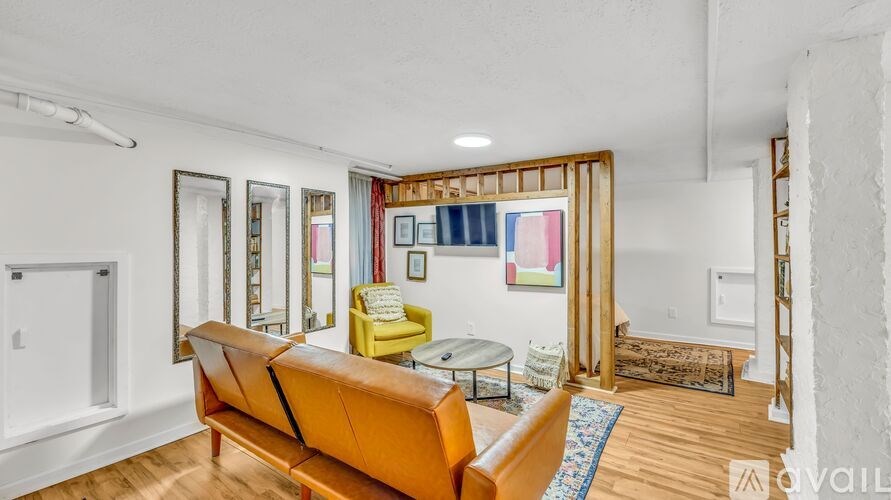 A living room with a yellow couch and a painting on the wall.