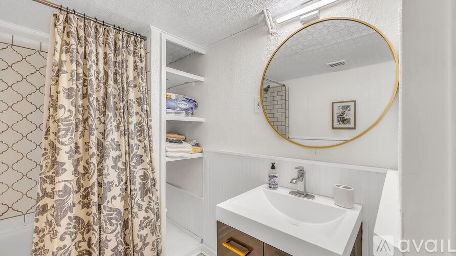 A bathroom with a white sink and a round mirror.