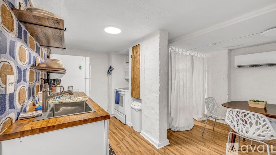 A kitchen with a sink, a refrigerator, and a dining table with chairs.