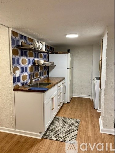 A kitchen with a white refrigerator and a counter with a blue and white patterned tile backsplash.