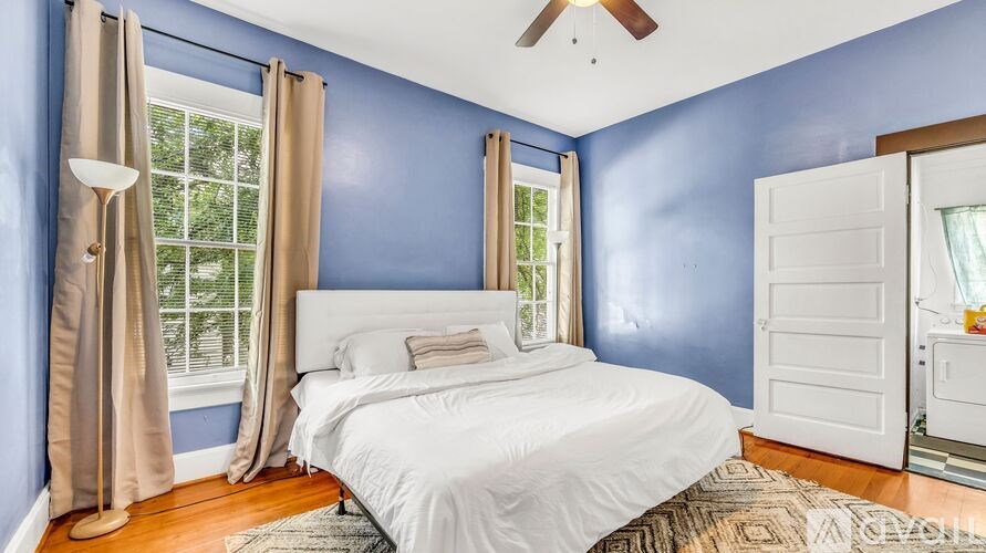 A bedroom with blue walls and a white bed.