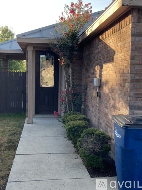 A house with a black door and a blue trash can.