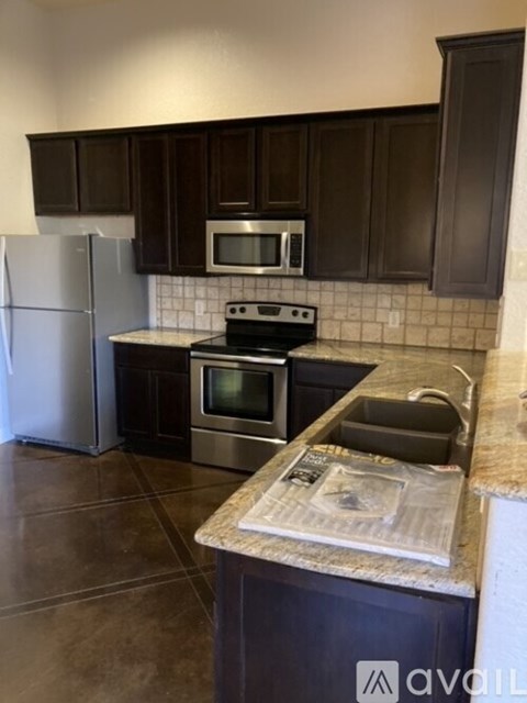 A kitchen with dark brown cabinets and a stainless steel refrigerator.