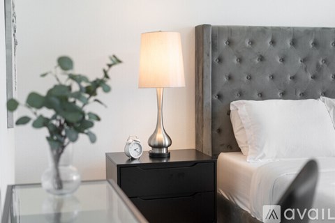 A bedroom with a bed, nightstand, and lamp.