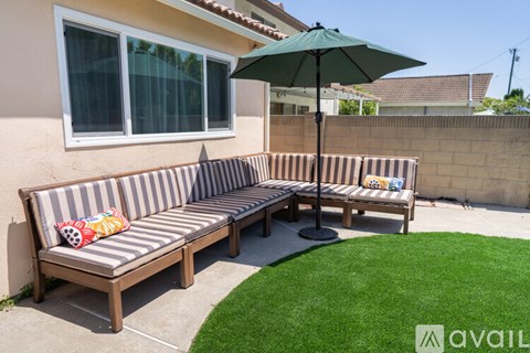 A patio with a striped couch and a green umbrella.