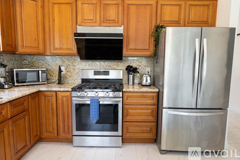 A kitchen with wooden cabinets and a stainless steel refrigerator.