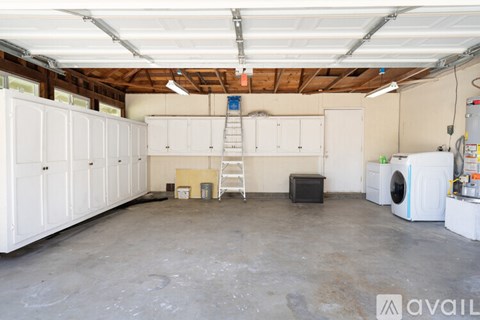 A large garage with white cabinets and a ladder.