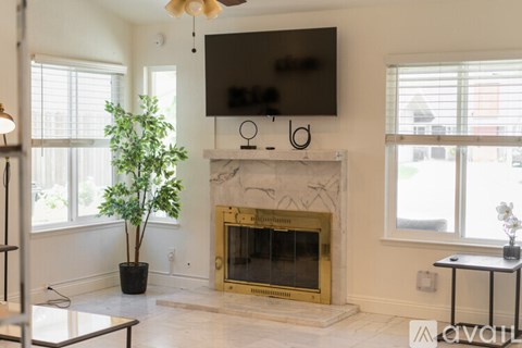 A living room with a fireplace and a flat screen TV mounted on the wall.