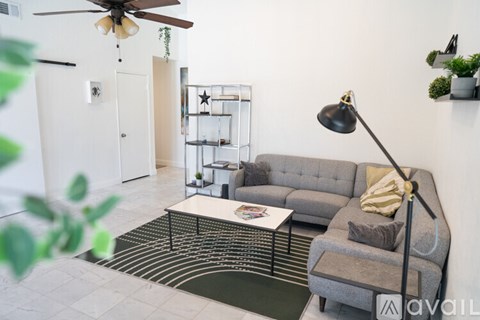 A living room with a grey couch, a coffee table, and a ceiling fan.