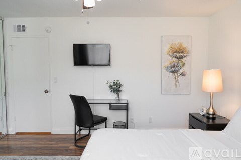 A bedroom with a bed, chair, and a painting on the wall.