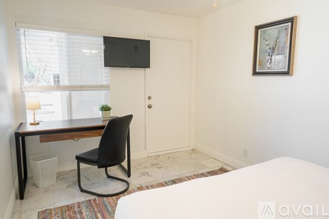 A room with a bed, desk, and chair.