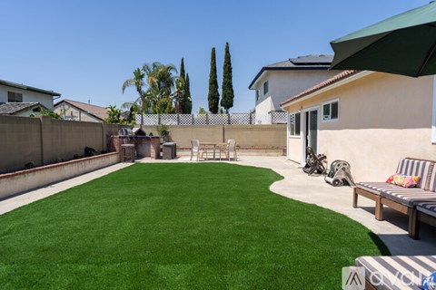 A backyard with a green lawn and a patio table.