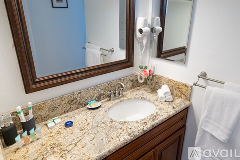 A bathroom with a granite countertop and a round sink.