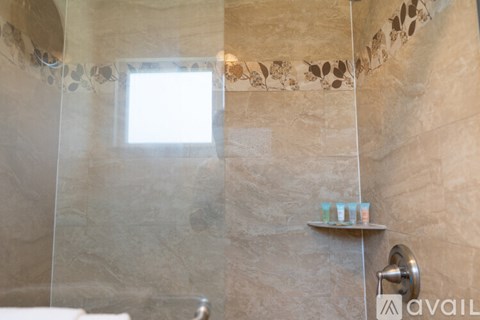 A bathroom with a shower area and a window.