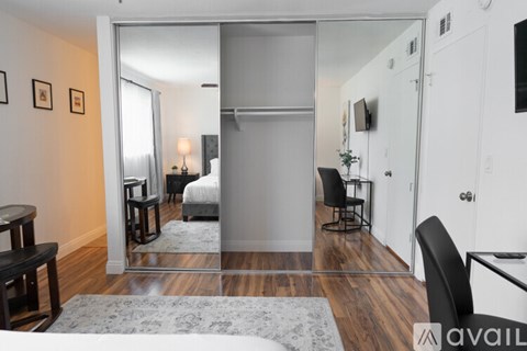 A bedroom with a bed, chair, and a mirror.