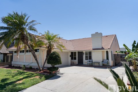 A house with a red tile roof and a white fence.