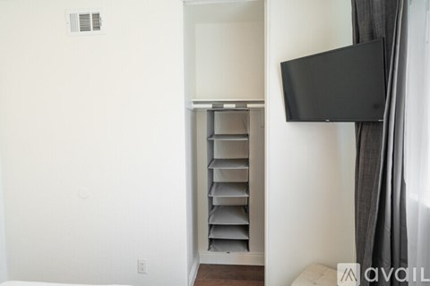 A black TV is mounted on a white wall above a white shelf.