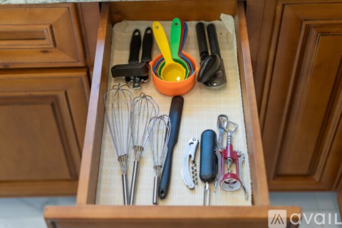 A drawer full of kitchen utensils including a whisk, spatula, and tongs.