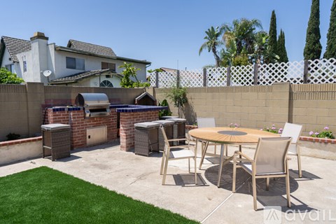 A patio with a table and chairs surrounded by a white fence.