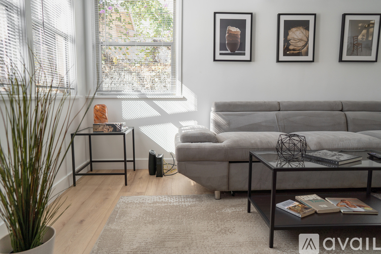 A living room with a grey sofa, a coffee table, and three framed pictures on the wall.