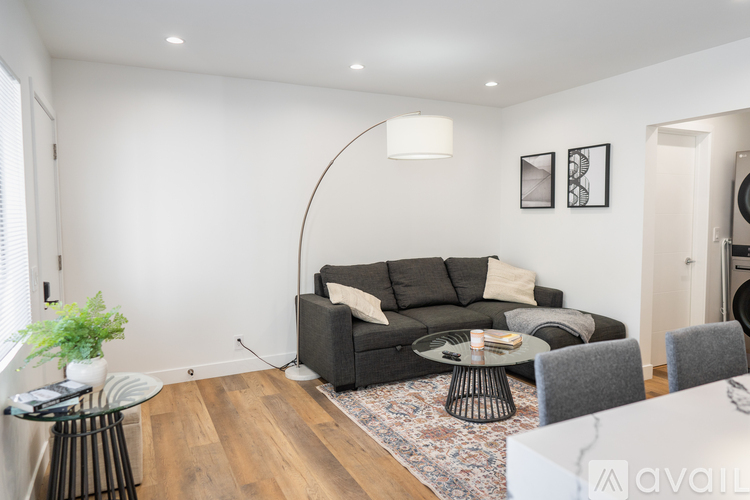 A living room with a grey couch, a small table, and a rug.