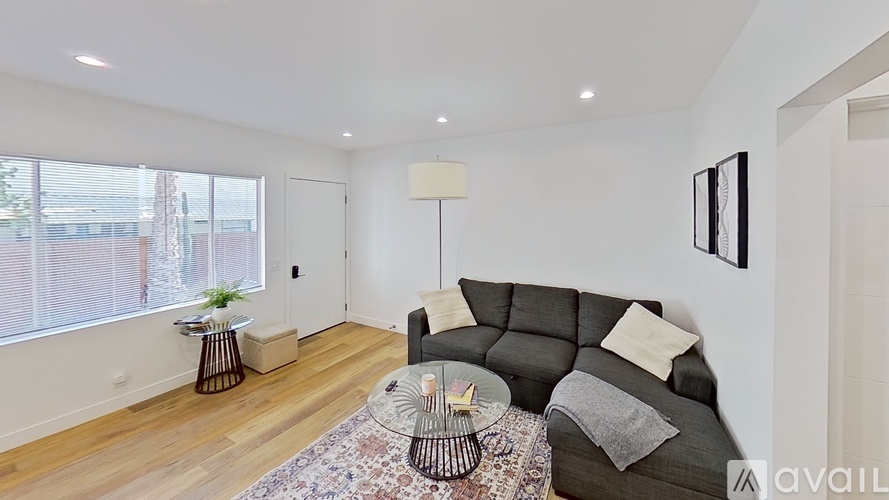 A living room with a grey couch, a glass table, and a rug.