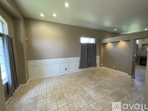 A spacious room with tiled flooring and a window with curtains.