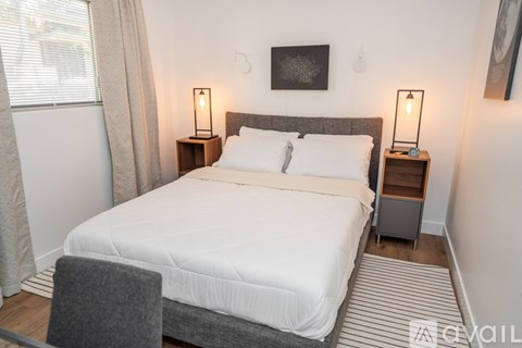 A bedroom with a large bed and two lamps on side tables.