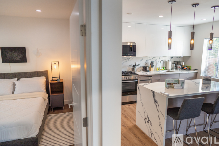 A modern bedroom with a large bed and a kitchen area with a bar.