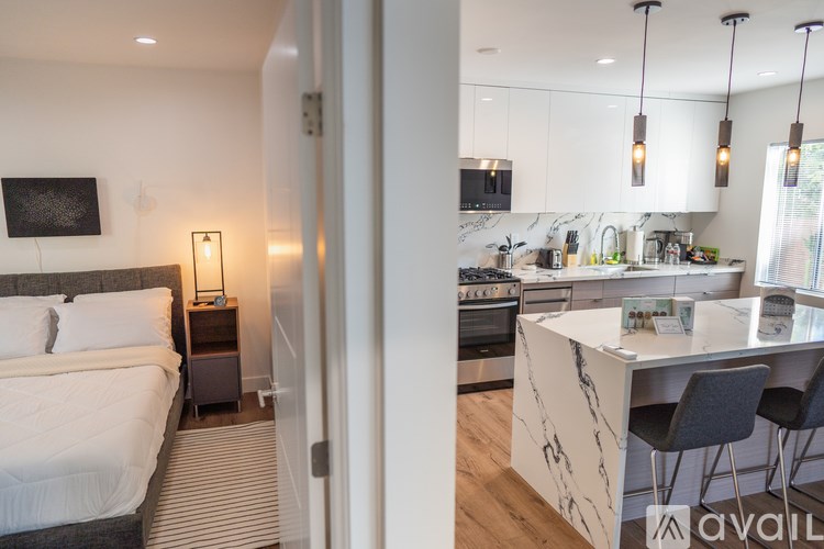 A modern bedroom with a large bed and a kitchen area with a bar.