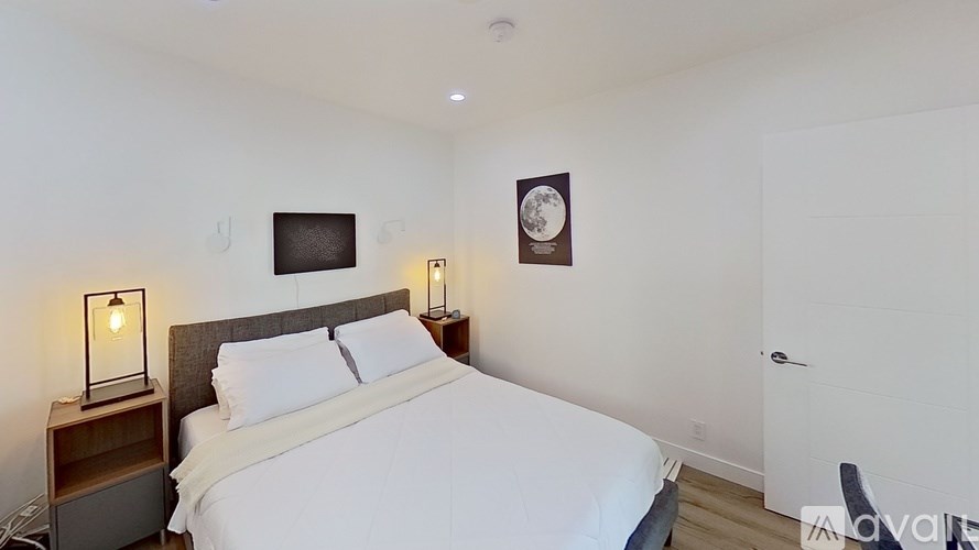 A bedroom with a bed, two lamps, and a clock on the wall.