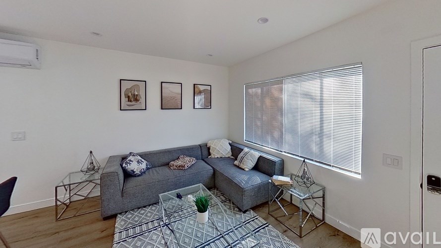 A living room with a grey couch, a blue couch, a coffee table, and three pictures on the wall.