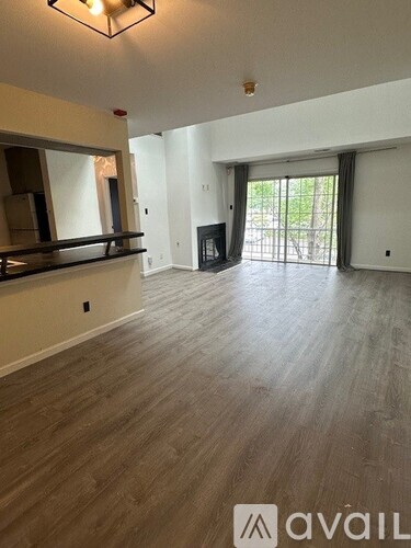 A spacious room with wooden flooring and white walls.
