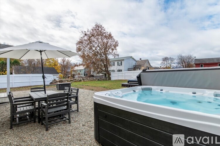 A hot tub is in the foreground of a backyard with a table and chairs.