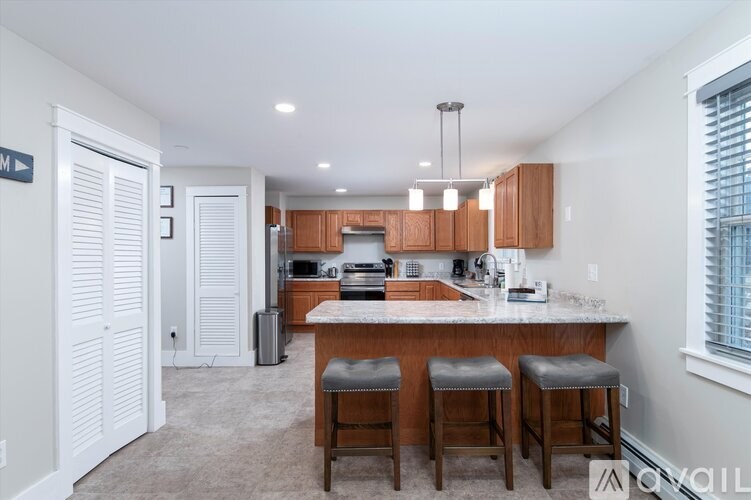 A kitchen with white walls and wooden cabinets.