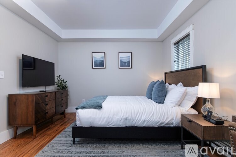 A bedroom with a large bed, a wooden dresser, and a television.