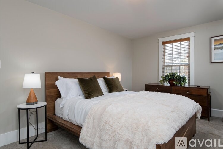 A bedroom with a large bed, a lamp, and a window.
