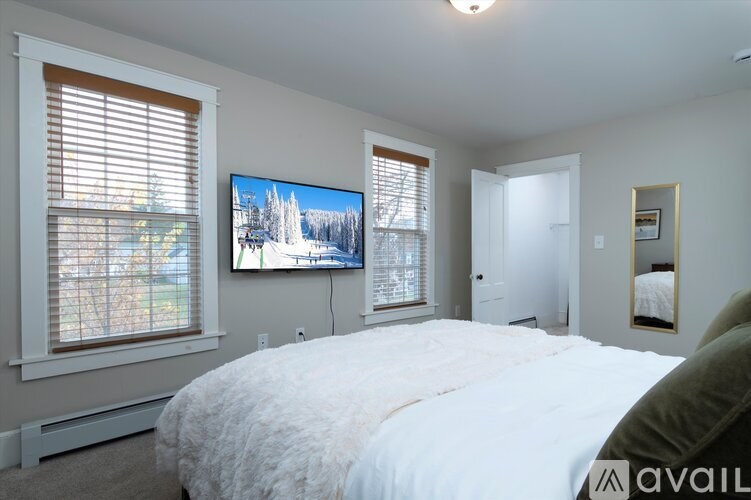 A bedroom with a large bed and a television mounted on the wall.