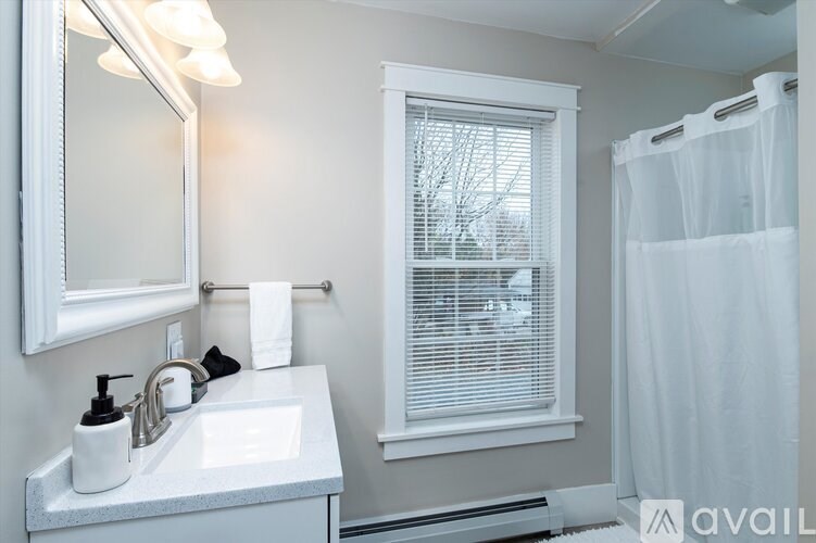 A bathroom with a white sink and a window with white blinds.