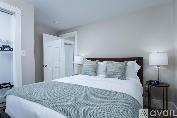 A bedroom with a large bed and two lamps on a side table.