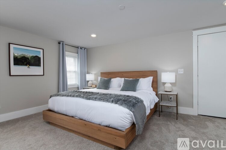 A bedroom with a large bed and a painting on the wall.