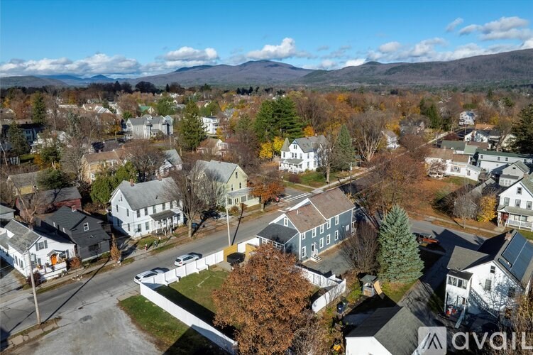 A small town with houses and trees in the foreground and mountains in the background.