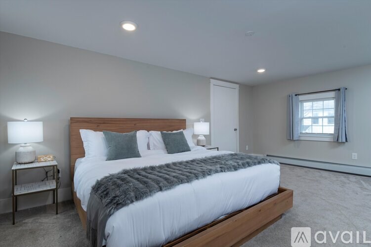 A bedroom with a large bed and a window with curtains.
