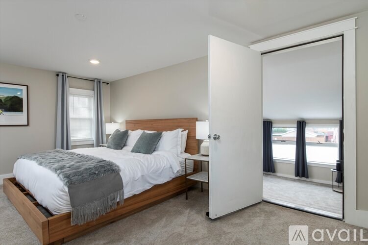 A bedroom with a large bed and a view of the street through the window.
