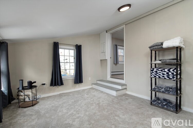 A room with a grey carpet, a black curtain, and a white door.