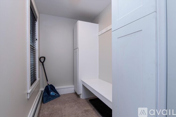 A broom is leaning against the wall in a white room.